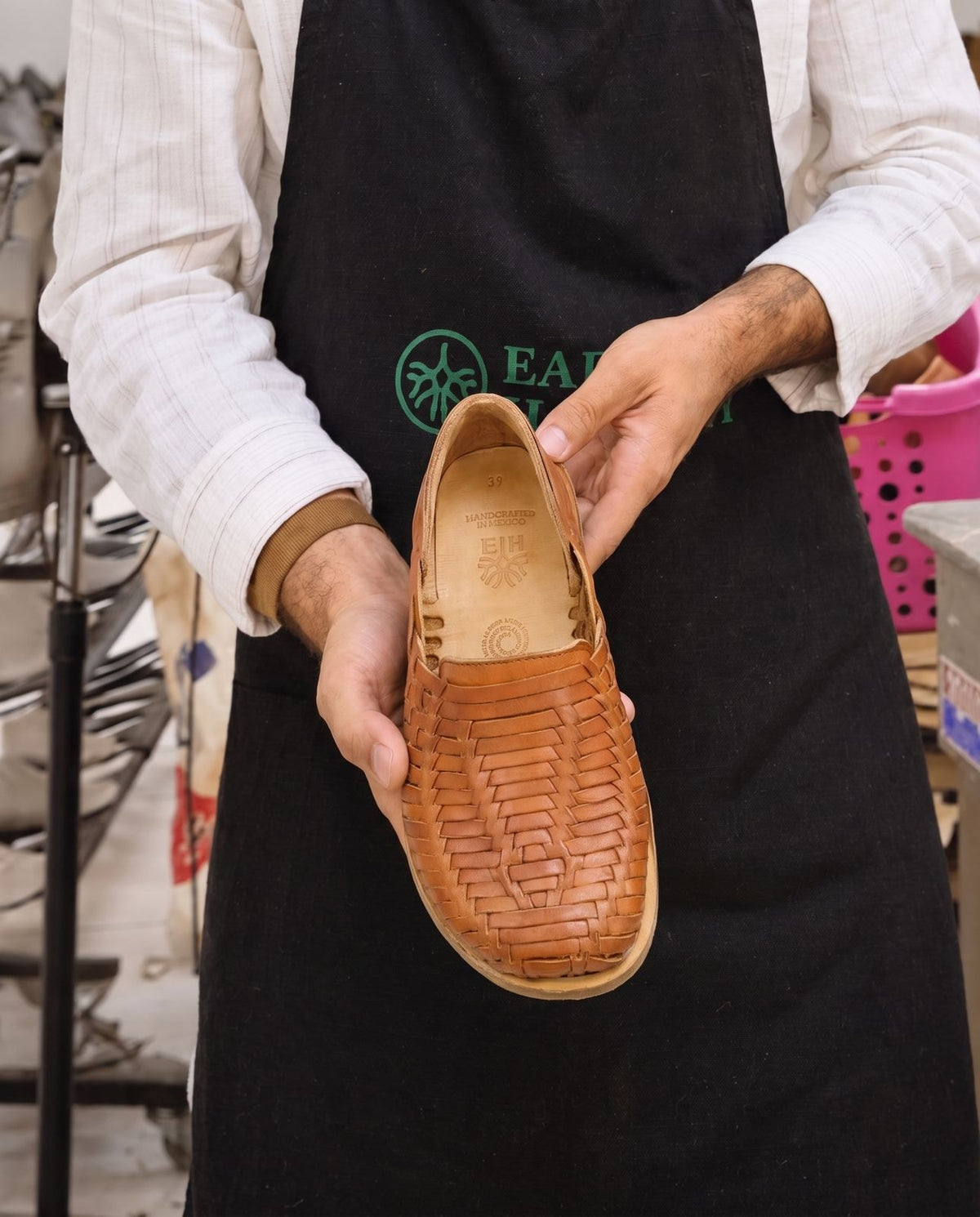 Artisan holding a finished pair of Earthing Harmony penny loafers