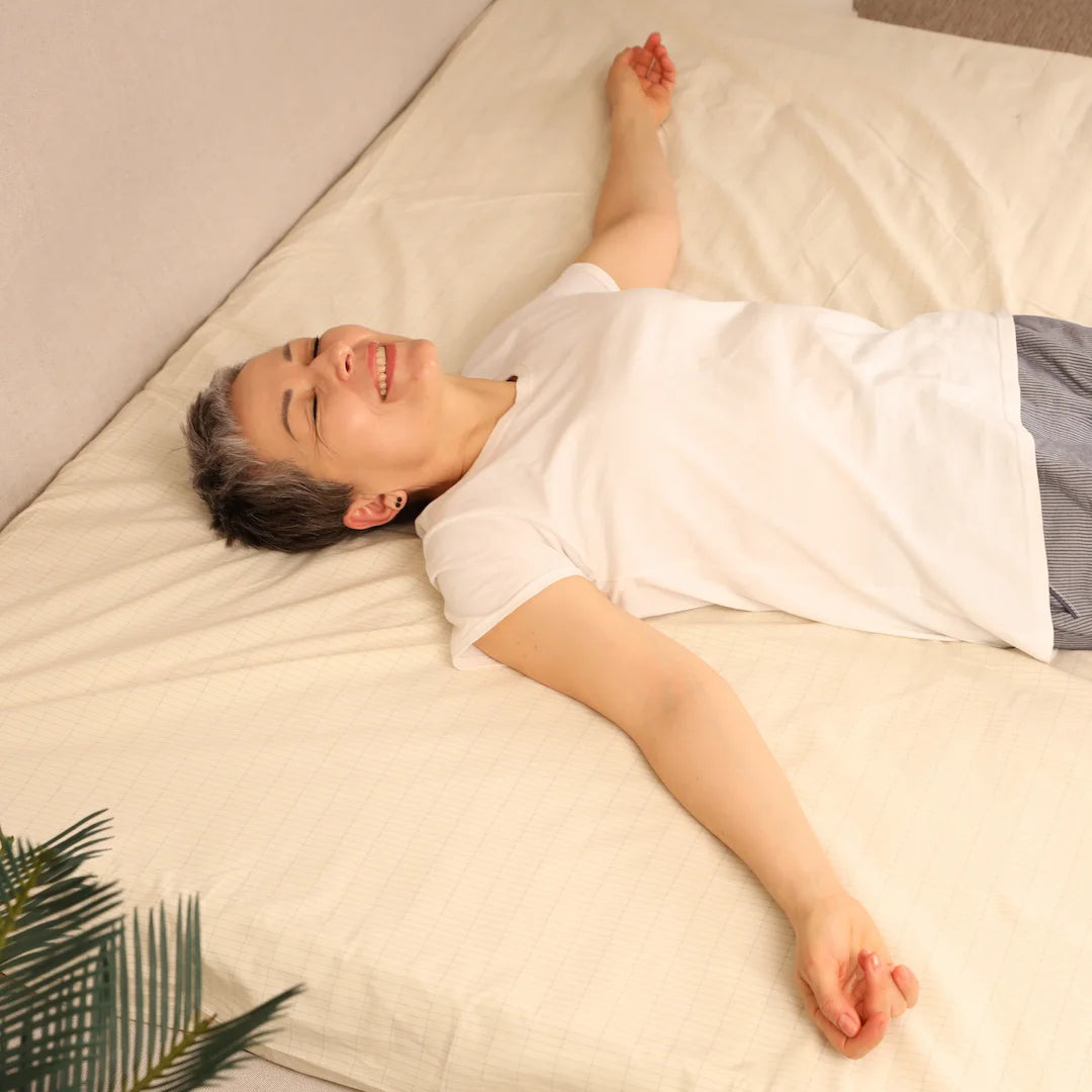 A woman lying on a grounding sheet, smiling